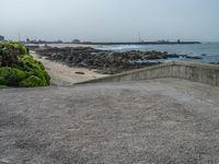 the empty parking lot has a water feature on it's wall and beach area with rock formations