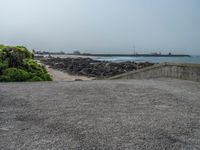 the empty parking lot has a water feature on it's wall and beach area with rock formations