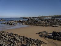 a rocky coast line near the ocean with boulders and rocks on the beach, looking out onto the water