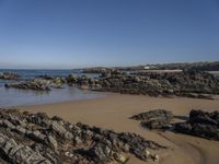 a rocky coast line near the ocean with boulders and rocks on the beach, looking out onto the water