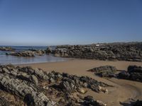 a rocky coast line near the ocean with boulders and rocks on the beach, looking out onto the water