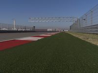 an empty track at a motorsports club with some red and white stripeing on it