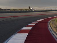 the track is red with white stripes as well as grass and shrubs behind it in front of an airport