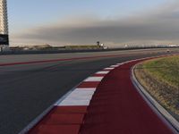 the track is red with white stripes as well as grass and shrubs behind it in front of an airport