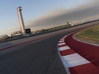 the track is red with white stripes as well as grass and shrubs behind it in front of an airport