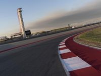 the track is red with white stripes as well as grass and shrubs behind it in front of an airport