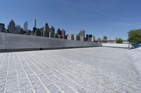 an empty walkway near some buildings on the other side of the water with skyscrapers in the background