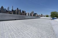 an empty walkway near some buildings on the other side of the water with skyscrapers in the background