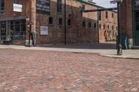 a brick street next to an older building and a metal pole with a stoplight on it