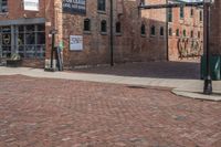 a brick street next to an older building and a metal pole with a stoplight on it