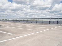 a car parked in the parking lot next to a bridge over water in front of the sky