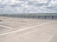 a car parked in the parking lot next to a bridge over water in front of the sky