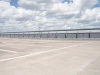 a car parked in the parking lot next to a bridge over water in front of the sky