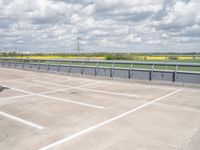 a car parked in the parking lot next to a bridge over water in front of the sky