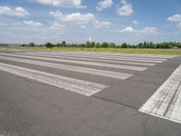 an empty runway in a city with grass on either side of the tarmac and a blue sky behind