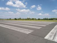 an empty runway in a city with grass on either side of the tarmac and a blue sky behind