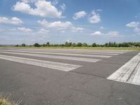 an empty runway in a city with grass on either side of the tarmac and a blue sky behind