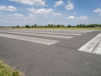 an empty runway in a city with grass on either side of the tarmac and a blue sky behind