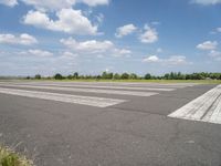 an empty runway in a city with grass on either side of the tarmac and a blue sky behind