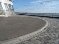 there is a black and white skateboarder riding in the empty place by the water