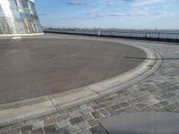 there is a black and white skateboarder riding in the empty place by the water