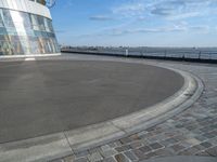 there is a black and white skateboarder riding in the empty place by the water