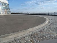 there is a black and white skateboarder riding in the empty place by the water