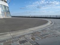 there is a black and white skateboarder riding in the empty place by the water