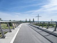 an elevated walkway going to a bridge with power lines across the road in the distance