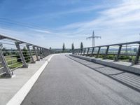 an elevated walkway going to a bridge with power lines across the road in the distance