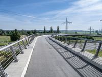 an elevated walkway going to a bridge with power lines across the road in the distance