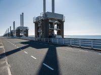 a man riding his bike on an empty road near a large building with an ocean view