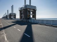 a man riding his bike on an empty road near a large building with an ocean view