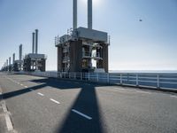 a man riding his bike on an empty road near a large building with an ocean view