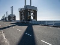 a man riding his bike on an empty road near a large building with an ocean view