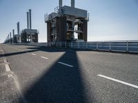 a man riding his bike on an empty road near a large building with an ocean view