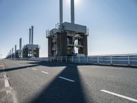 a man riding his bike on an empty road near a large building with an ocean view