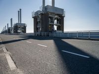 a man riding his bike on an empty road near a large building with an ocean view