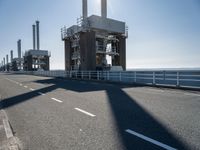 a man riding his bike on an empty road near a large building with an ocean view