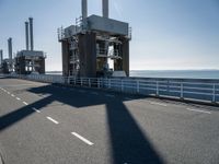 a man riding his bike on an empty road near a large building with an ocean view