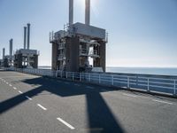 a man riding his bike on an empty road near a large building with an ocean view