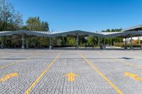 two white awnings in a parking lot with some trees on the ground,