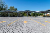 two white awnings in a parking lot with some trees on the ground,