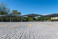 two white awnings in a parking lot with some trees on the ground,