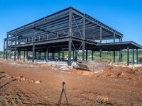 a picture of a building being built on a field near a forest in the background