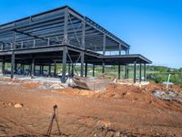 a picture of a building being built on a field near a forest in the background