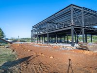 a picture of a building being built on a field near a forest in the background