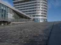 a modern building with a staircase that goes to it's top floor and is standing next to the steps on the cobblestone