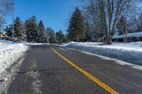 a street is covered with snow and trees along the road with a stop sign on the right side