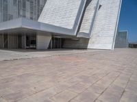 a white building with several steps and large glass panels in the facade is a mosaic that depicts a man